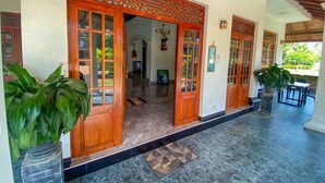 Una entrada de edificio con puertas de madera, piso de baldosas y plantas en macetas.
