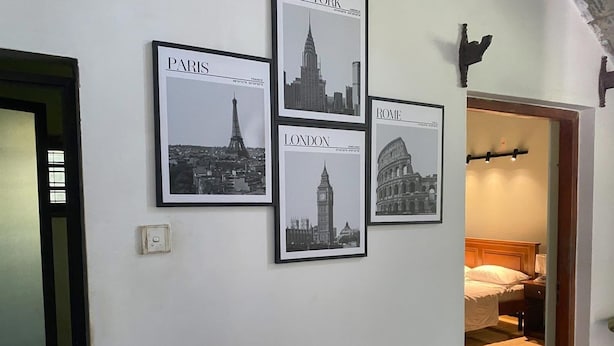 Un pasillo con carteles enmarcados de paisajes urbanos de París, Londres y Roma.