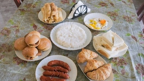 Una mesa con diversos alimentos, como panes, salchichas, arroz y sándwiches.