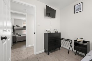 A bedroom with a bunk bed, a dresser, a TV mounted on the wall, and a framed picture. - FAMILY FUN BEACH HOUSE (Wildwood)