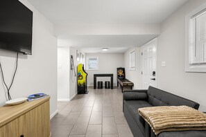 A modern living room with a flat-screen TV, a sofa, a gaming console, and a pool table. - FAMILY FUN BEACH HOUSE (Wildwood)