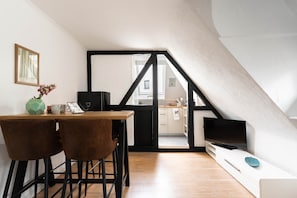 Une cuisine moderne avec un coin repas, un téléviseur et un escalier menant à l’étage supérieur.