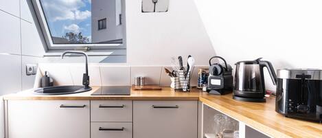 A modern kitchen with a skylight, a coffee maker, and a kettle on the counter.