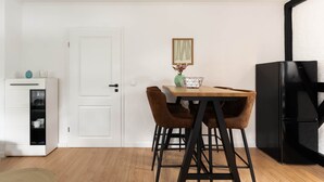 A compact kitchen with a white door, a dining table with two chairs, a black refrigerator, and a small cabinet with shelves. - Central vacation apartment in Arnsberg's old town (Arnsberg)