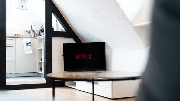 A modern living room with a white sofa, a black television, and a kitchen area in the background. - Central vacation apartment in Arnsberg's old town (Arnsberg)