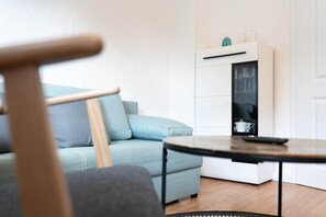 Un salon moderne avec un canapé bleu clair, une chaise en bois, une petite table ronde et un meuble blanc doté de portes en verre.