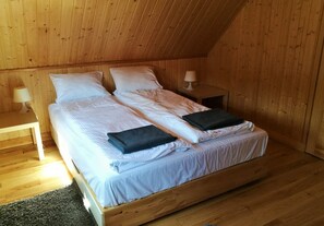 Ett rum med träpanel på väggarna, en säng, två sängbord och en lampa.