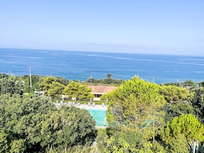 A pool surrounded by lush greenery, overlooking a clear blue sea. - Stella Marina by Interhome (Castiglioncello)