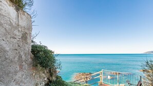 Eine Steintreppe führt zu einer Küstenregion mit einer Bank und einem Geländer mit Blick aufs Meer.