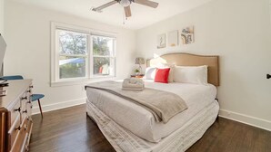 Ein Schlafzimmer mit Bett, Deckenventilator, Fenster und Kommode.