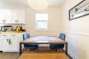 A dining area with a table, chairs, a hanging light fixture, and a window.