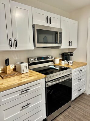 A modern kitchen with white cabinets, a stainless steel microwave, a toaster, and an oven. - Park Circle Charmer With Backyard Oasis (North Charleston)