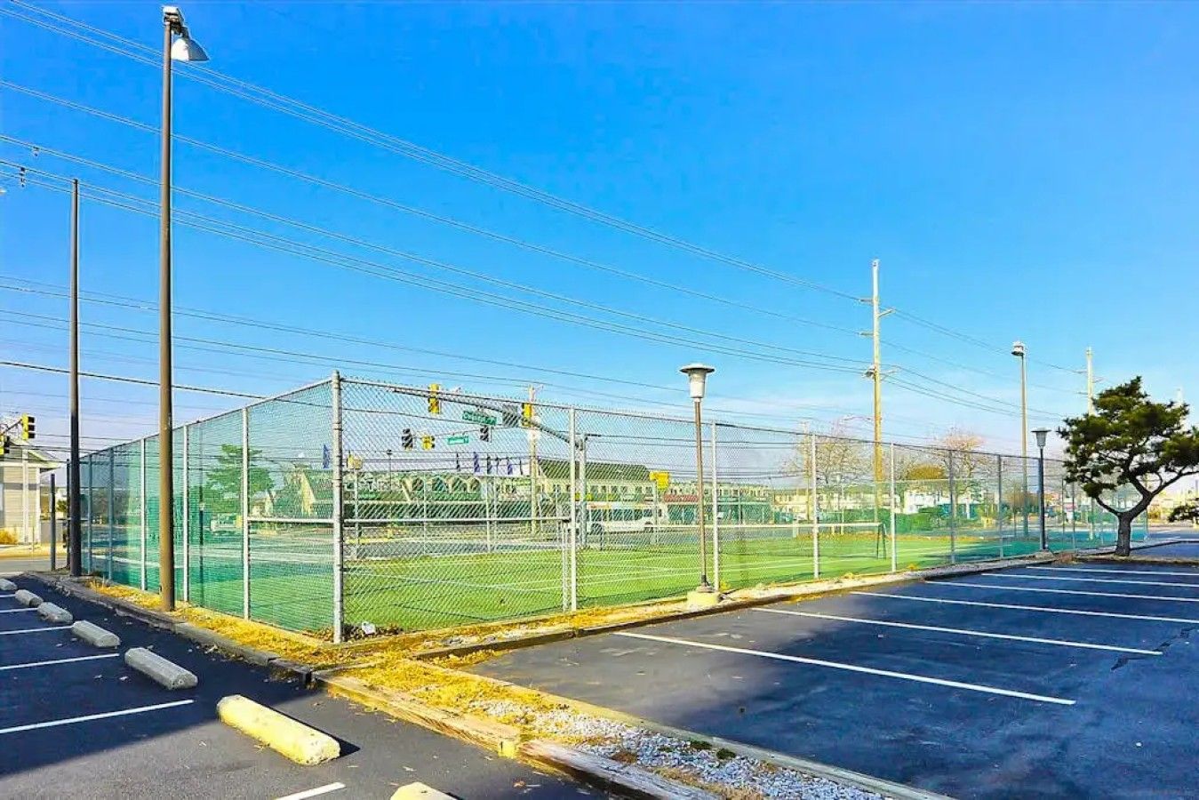 Ein eingezäuntes Sportfeld mit einem Parkplatz im Vordergrund.