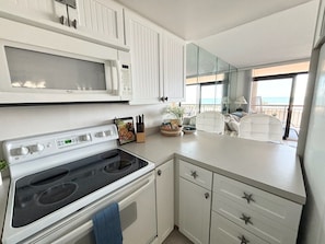 A modern kitchen with a stove, microwave, and white cabinets.
