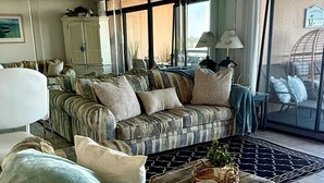 A living room with a sofa set, a large window, and a view of the outside. - Oceanfront Condo with Heated Pool, 2 Balconies, Beach Access & Courts (Ocean City)