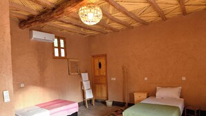 Ein gemütliches Hotelzimmer mit zwei Betten, einer Holzbalkendecke, einer Hängeleuchte und einem kleinen Tisch.