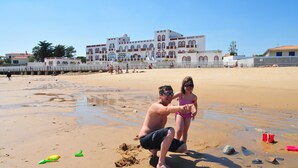 A sandy beach with a large building in the background.