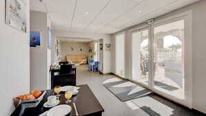 A hotel lobby with a dining area, a reception desk, and a view of the outdoors.