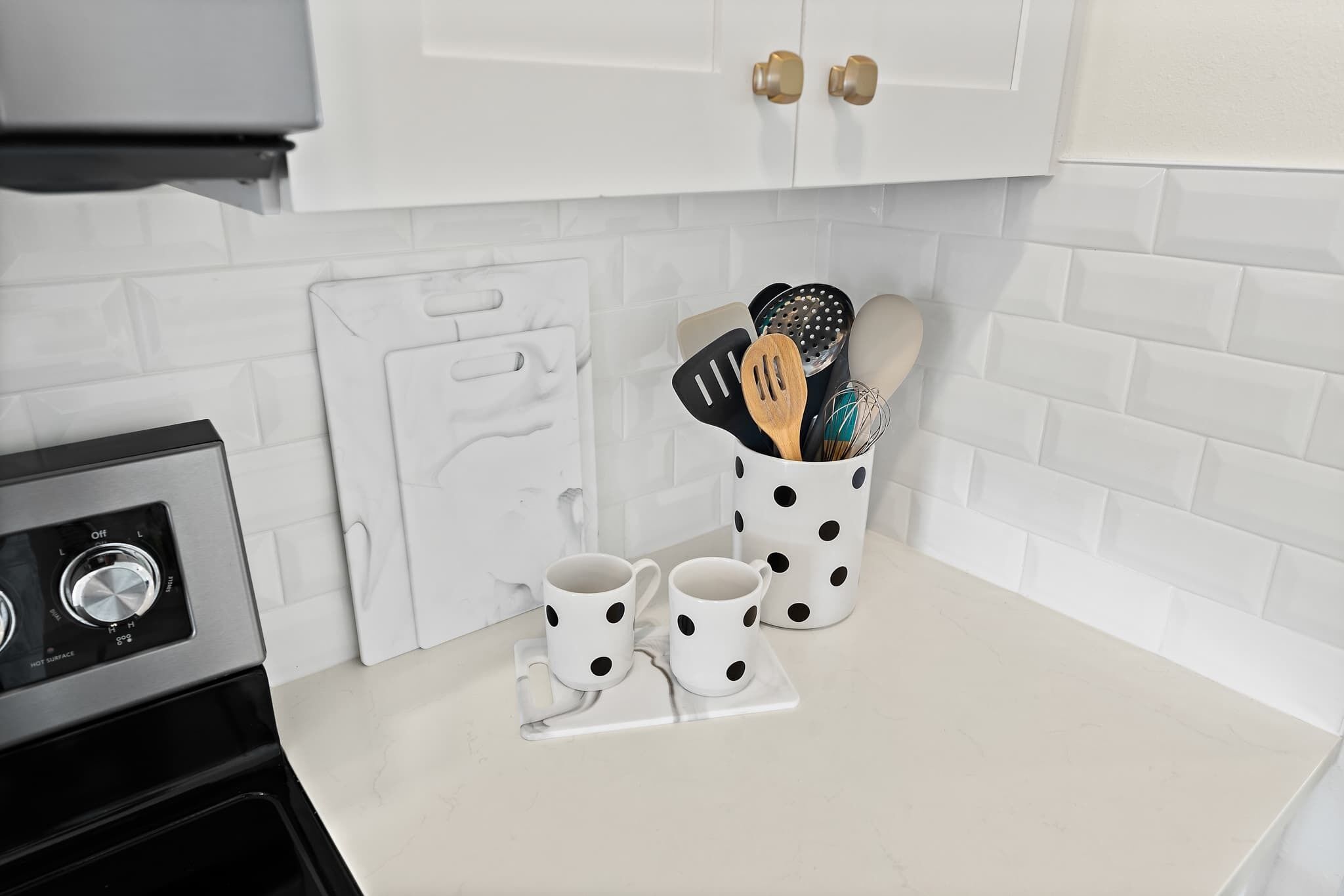 Una cocina con armarios blancos, encimera blanca y una cafetera.