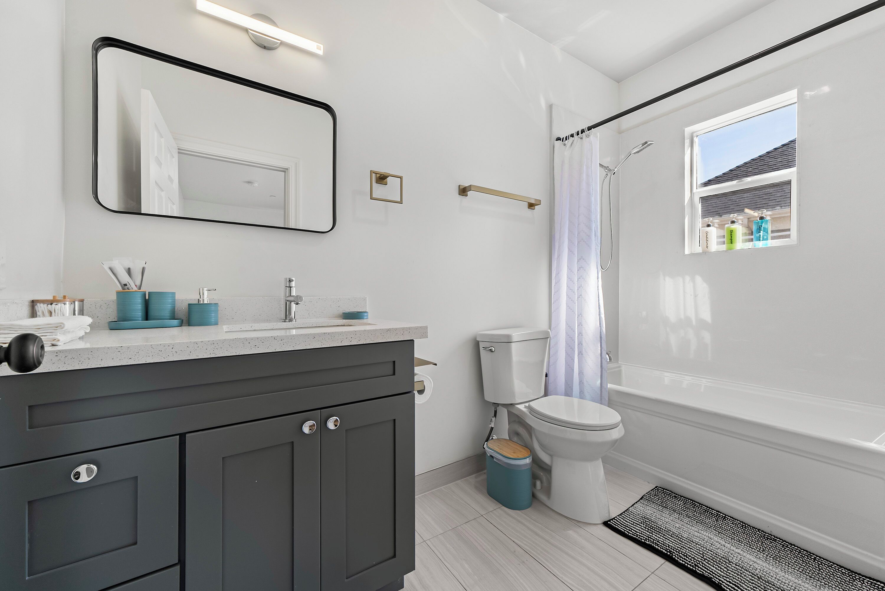 Un bagno moderno con un mobile lavabo grigio, un water e una tenda per la doccia.