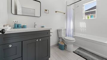 Un bagno moderno con un mobile lavabo grigio, un water e una tenda per la doccia.