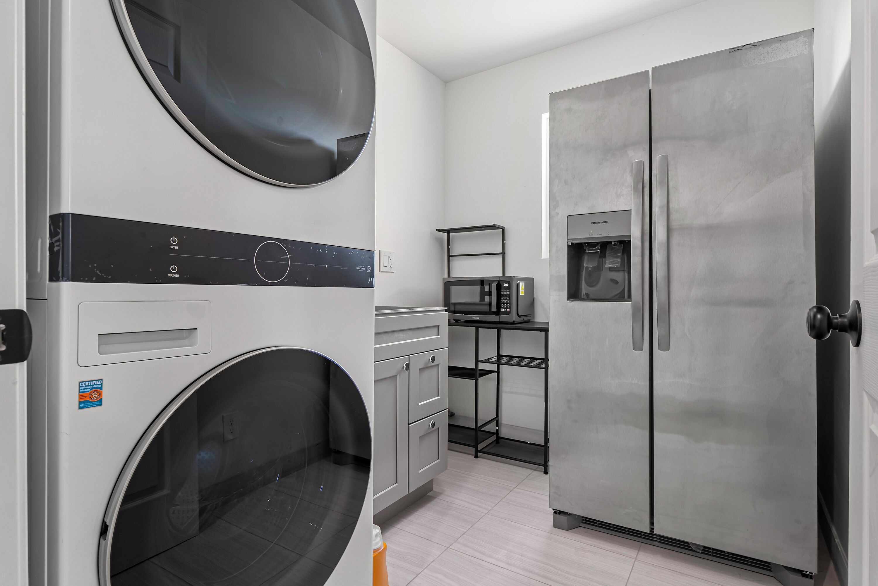Un cuarto de lavandería con lavadora, secadora y refrigerador.