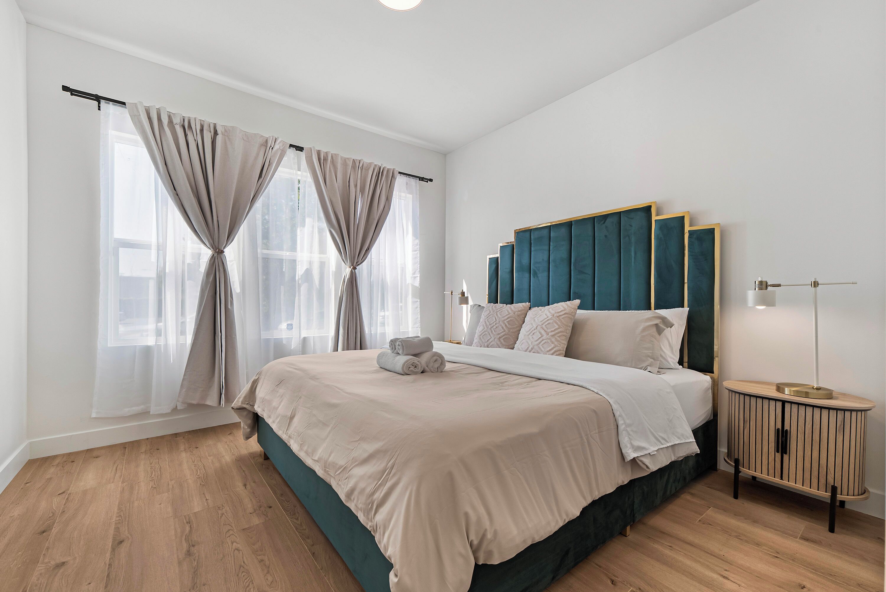 A bedroom with a large bed, a headboard, a bedside table, and a nightstand.