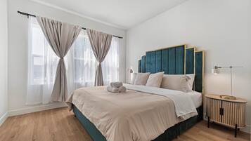 A bedroom with a large bed, a headboard, a bedside table, and a nightstand.