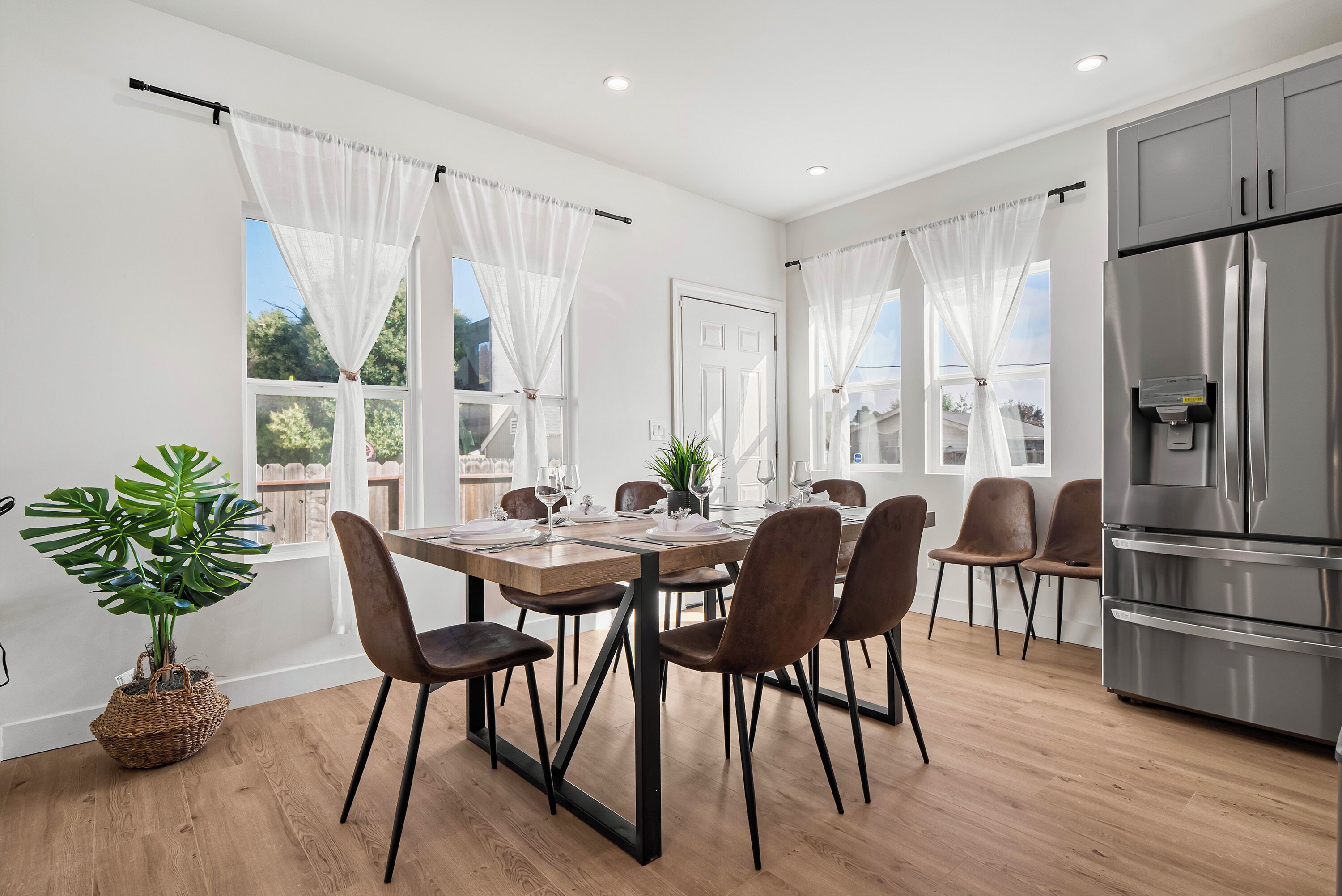 A modern dining area with a wooden table, brown chairs, and a large refrigerator.