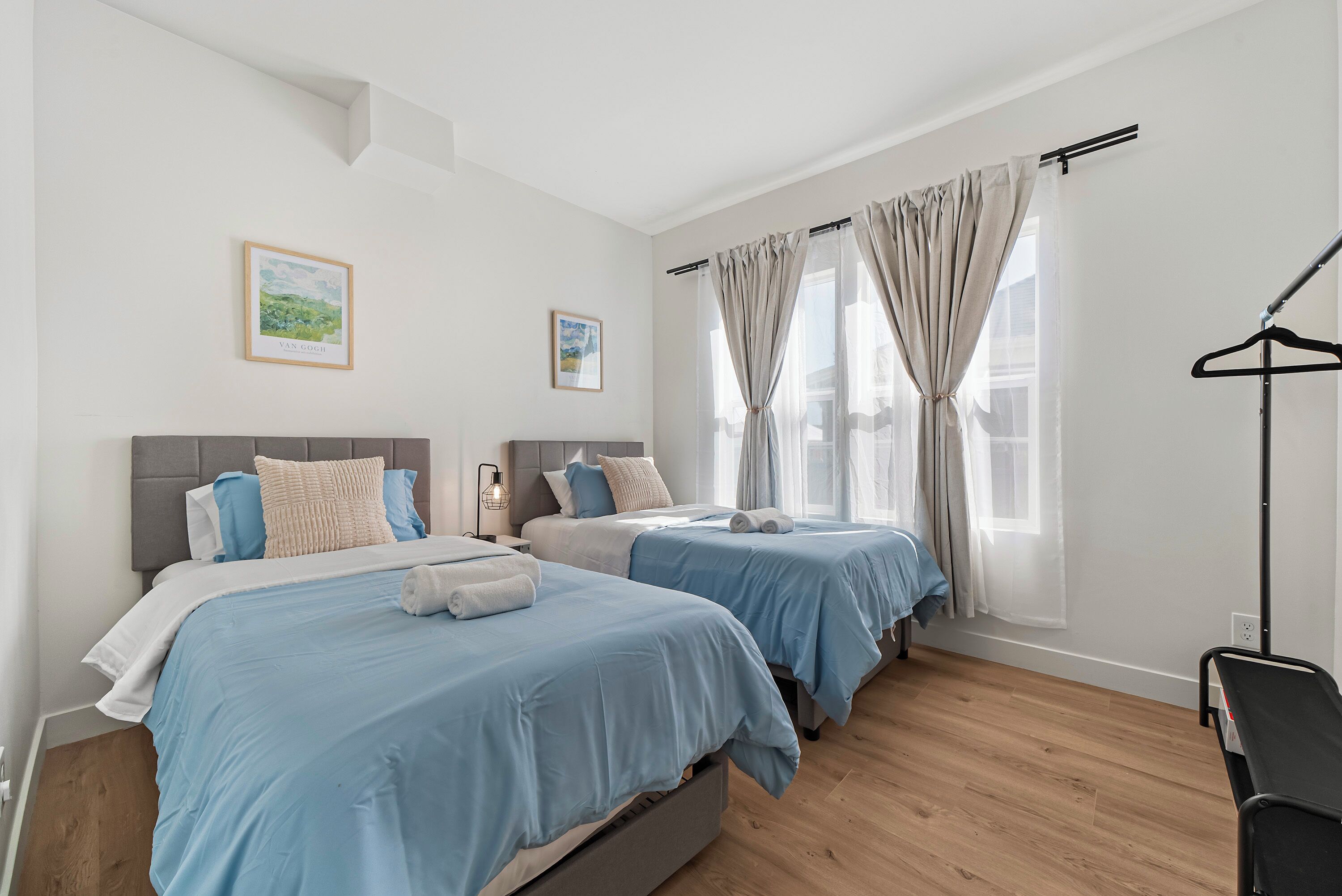 A hotel room with two beds, a wardrobe, and a bedside table.