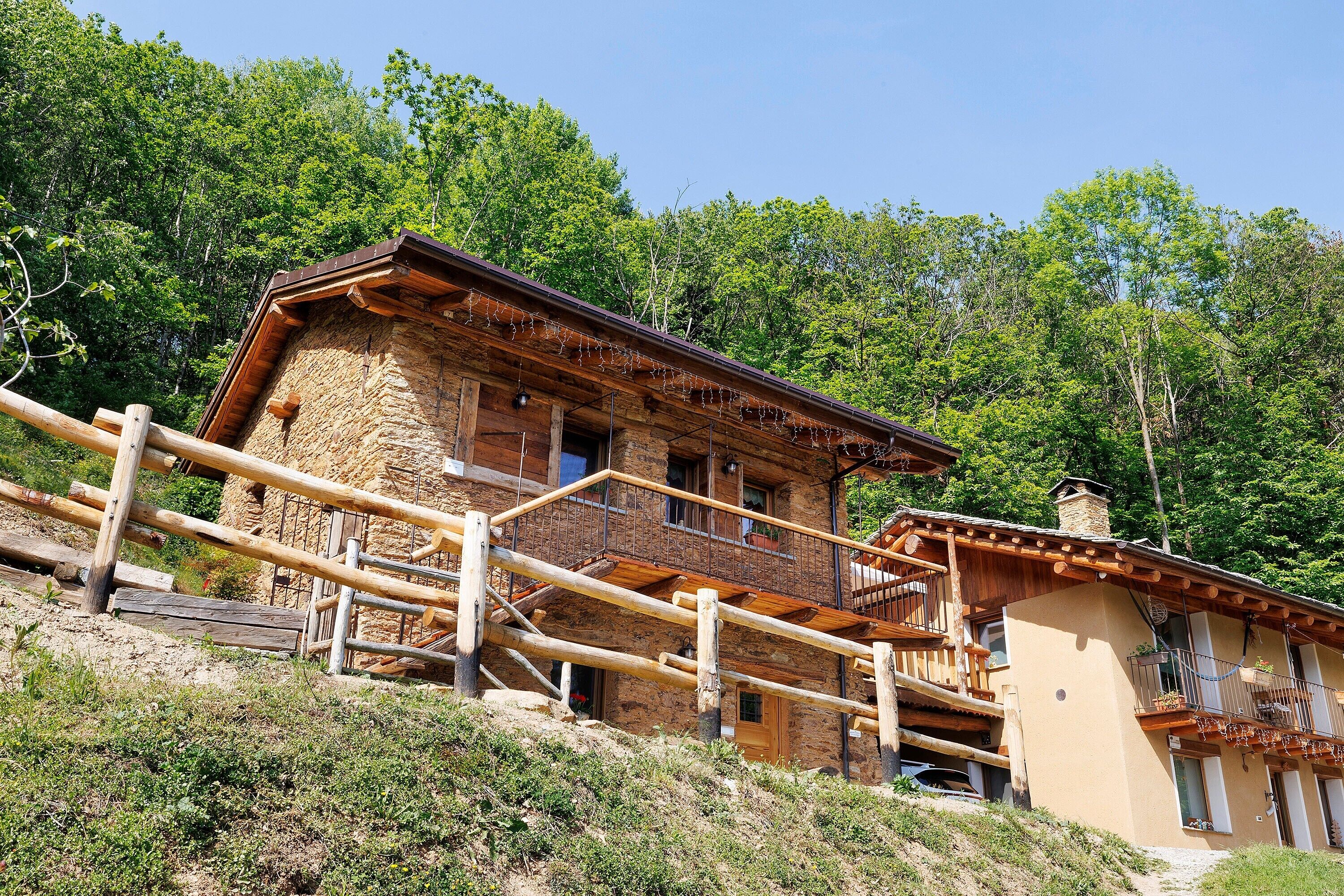 A rustic wooden building with a balcony, surrounded by trees.