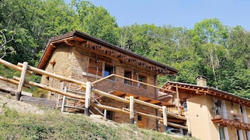 A rustic wooden building with a balcony, surrounded by trees.