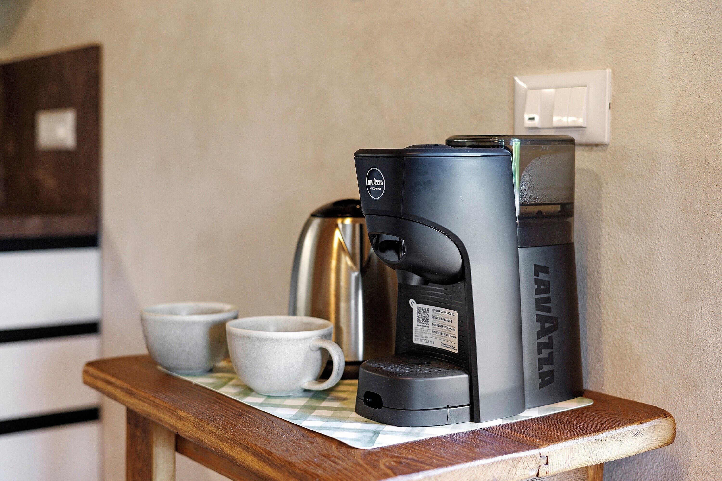 Une machine à café est posée sur une table, à côté de deux tasses.