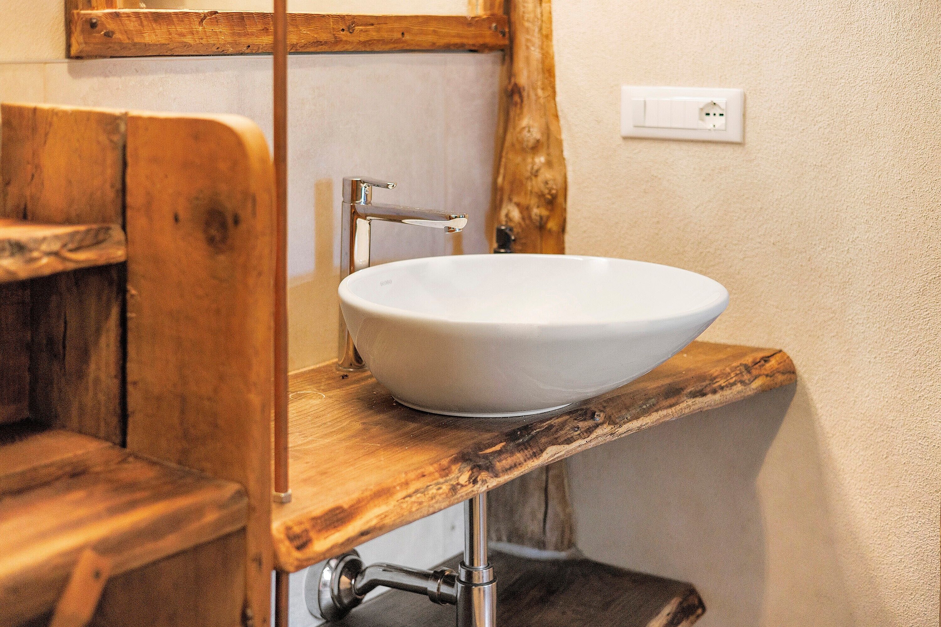 Ein Badezimmer mit einem Holzwaschtisch, einem weißen Waschbecken und einem spiegelnden Holzrahmen.