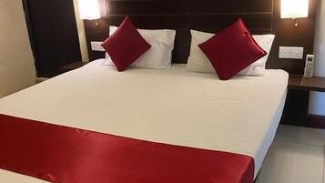 A hotel room with a large bed, red and white bedding, two bedside lamps, and a nightstand with a phone.