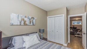 Un dormitorio con cama, mesita de noche, lámpara, armario y un cuadro en la pared.