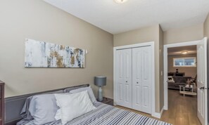 Ein Schlafzimmer mit Bett, Nachttisch, Lampe, Kleiderschrank und einem Bild an der Wand.