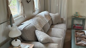Una habitación acogedora con un sofá, una lámpara, una mesita y una mesita auxiliar con libros y adornos.