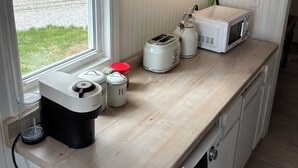 Una cocina compacta con lavadora, microondas, tostadora y cafetera en la encimera.