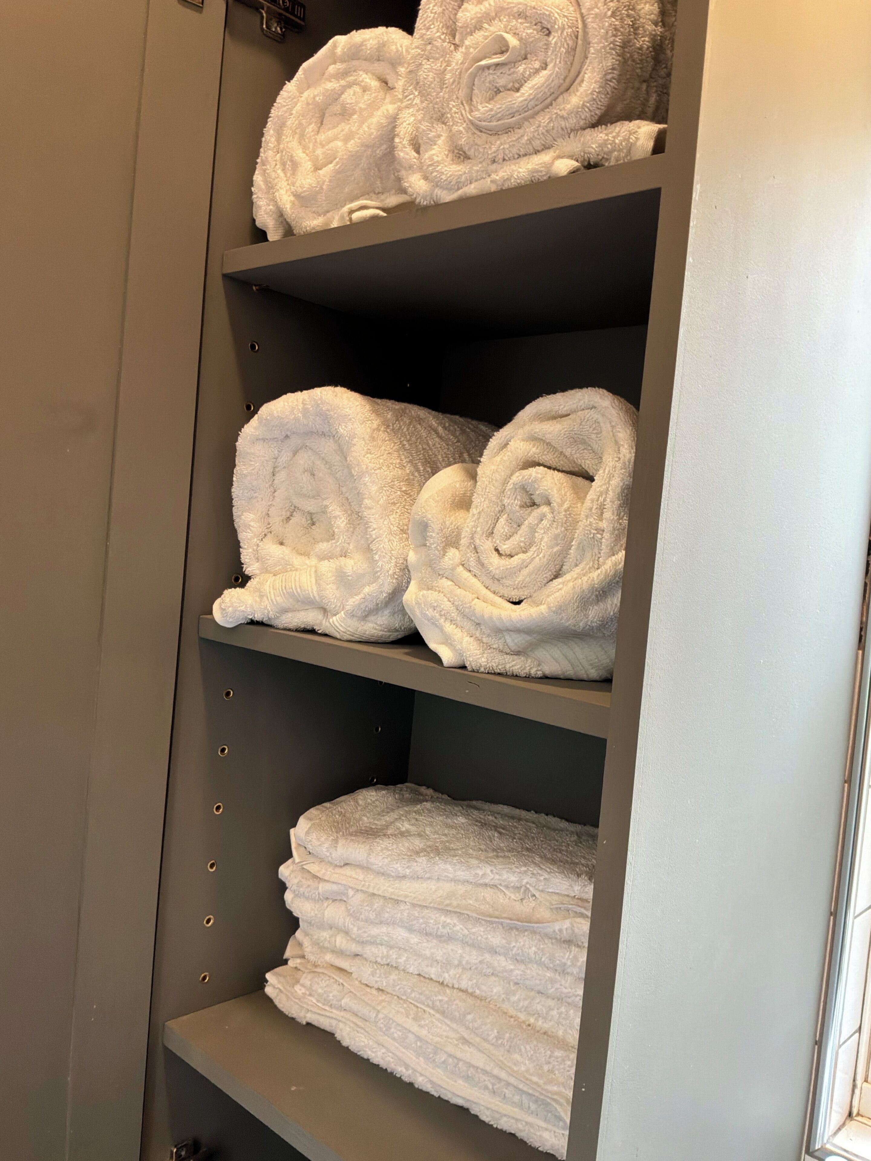 A storage unit with shelves holding neatly rolled white towels.