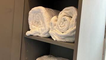 A storage unit with shelves holding neatly rolled white towels.