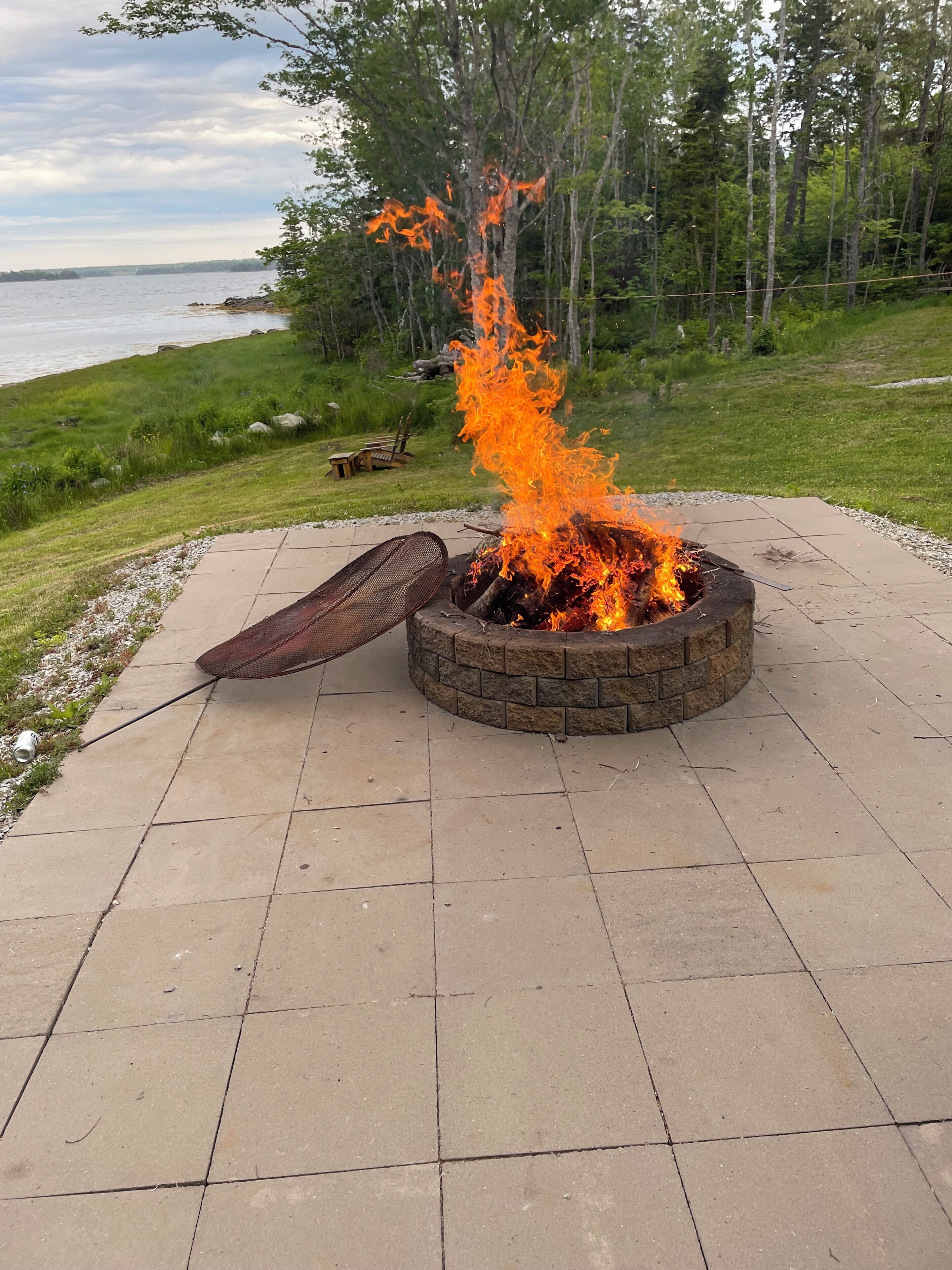 A fire pit with logs, surrounded by a paved patio.