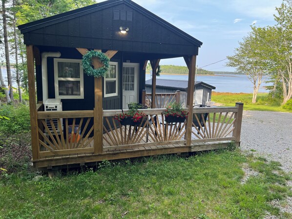 A small wooden cabin with a porch, a wreath, and flower baskets.