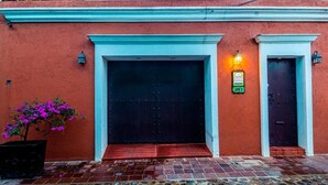 A building with a red exterior, a black door, and a small entrance. - Casa del Barrio (Oaxaca)