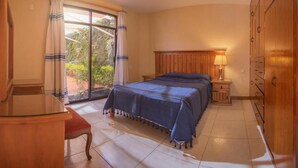 A bedroom with a bed, a desk, a wardrobe, and a window with curtains. - Casa del Barrio (Oaxaca)