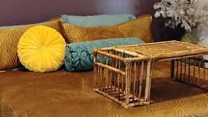 A bed with a patterned cover, a small wooden stool, and a vase with flowers.