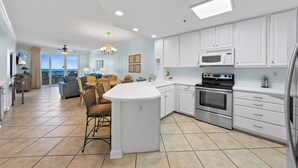 A spacious kitchen with white cabinetry, a central island, and a view to the outside. - Beautiful Beach Front Condo with Breathtaking Views (Orange Beach)