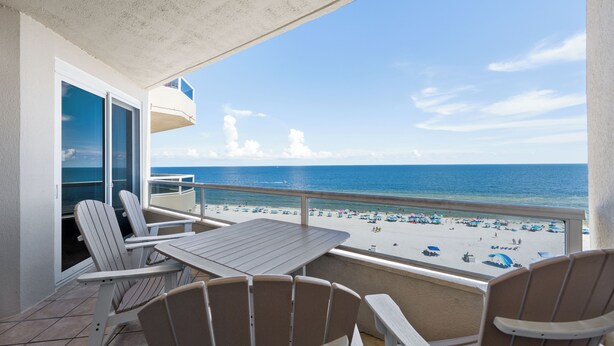 A balcony with a view of the beach, equipped with a table and chairs. - Beautiful Beach Front Condo with Breathtaking Views (Orange Beach)