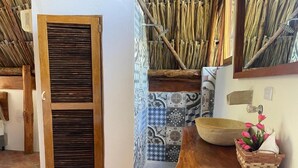 Una habitación con puerta de madera, baldosas con diseño, pared tejida, una mesa de madera con un cuenco y una cesta con flores.