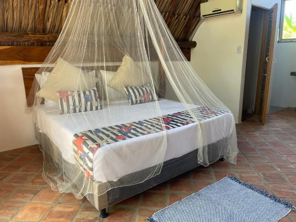 A bed with a mosquito net, pillows, and a checkered blanket.
